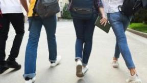 Des jeunes, vus de dos, marchent dans une même direction sur une route